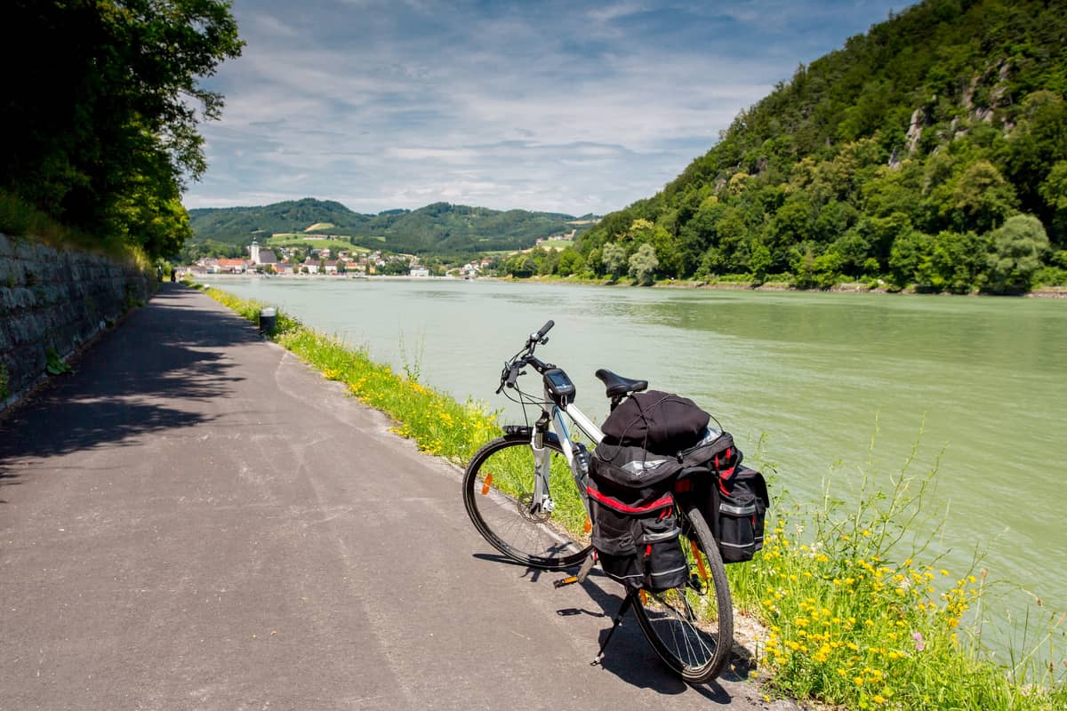 Fahrrad mit Gepäck auf einer Straße an einem Fluss