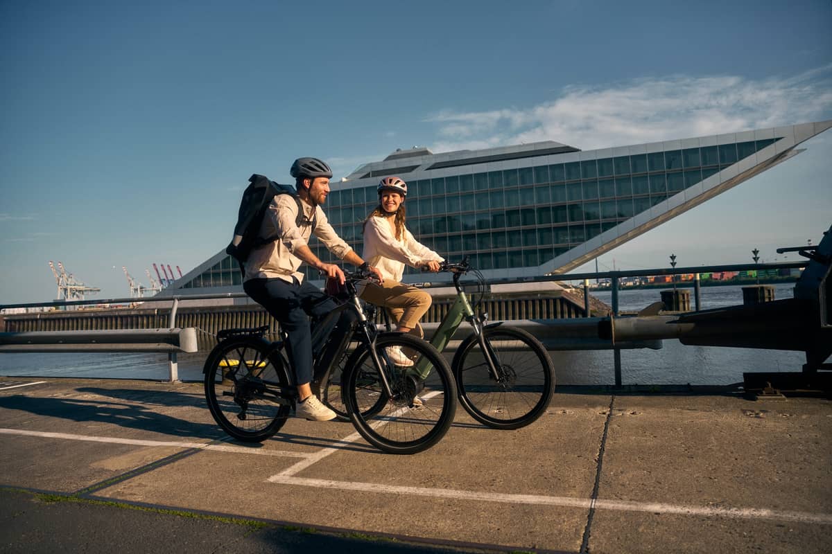 Couple riding e-bikes in front of modern building