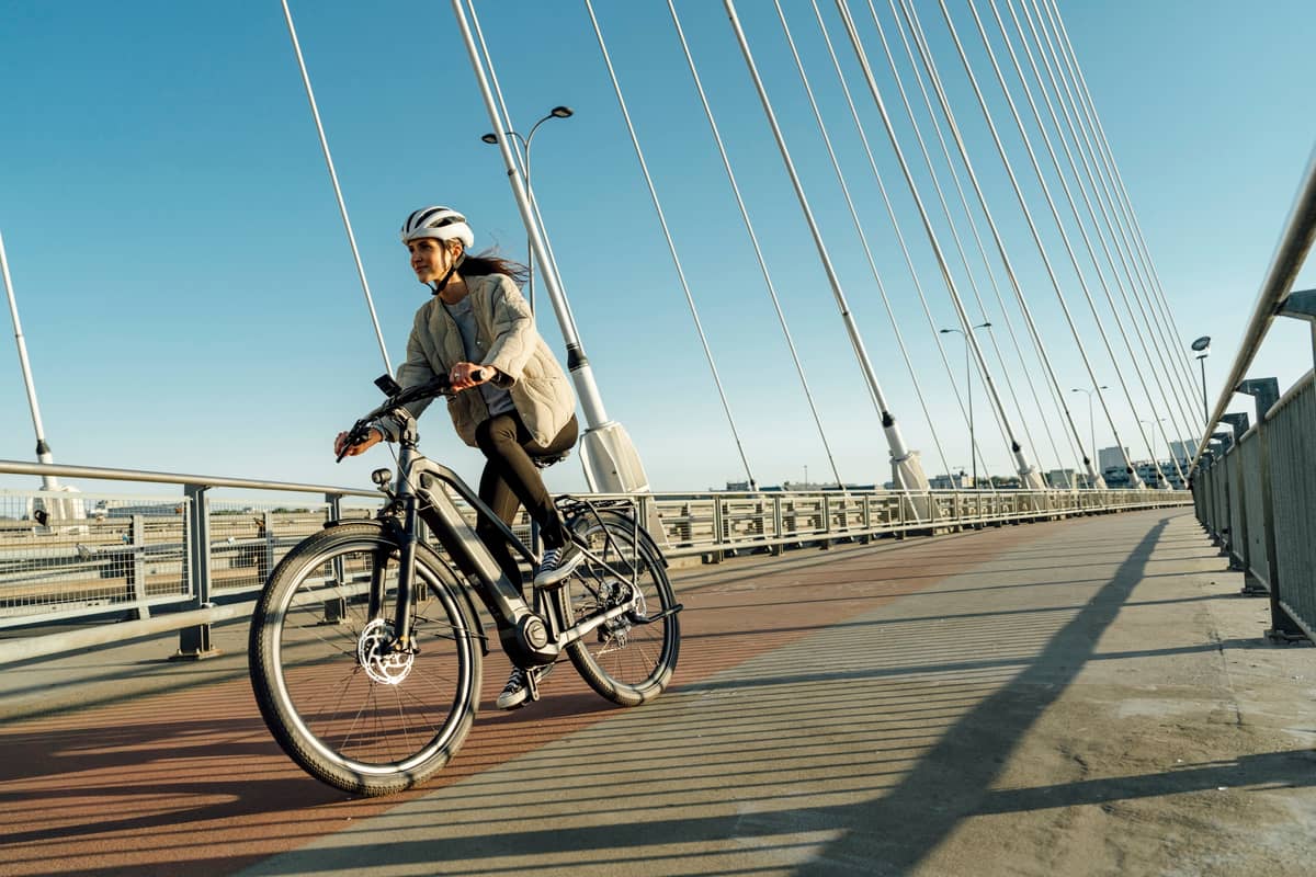 Frau fährt auf E-Bike über moderne Brücke