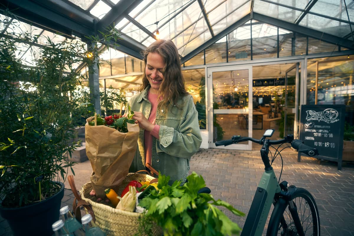 Young woman puts groceries in the bike basket