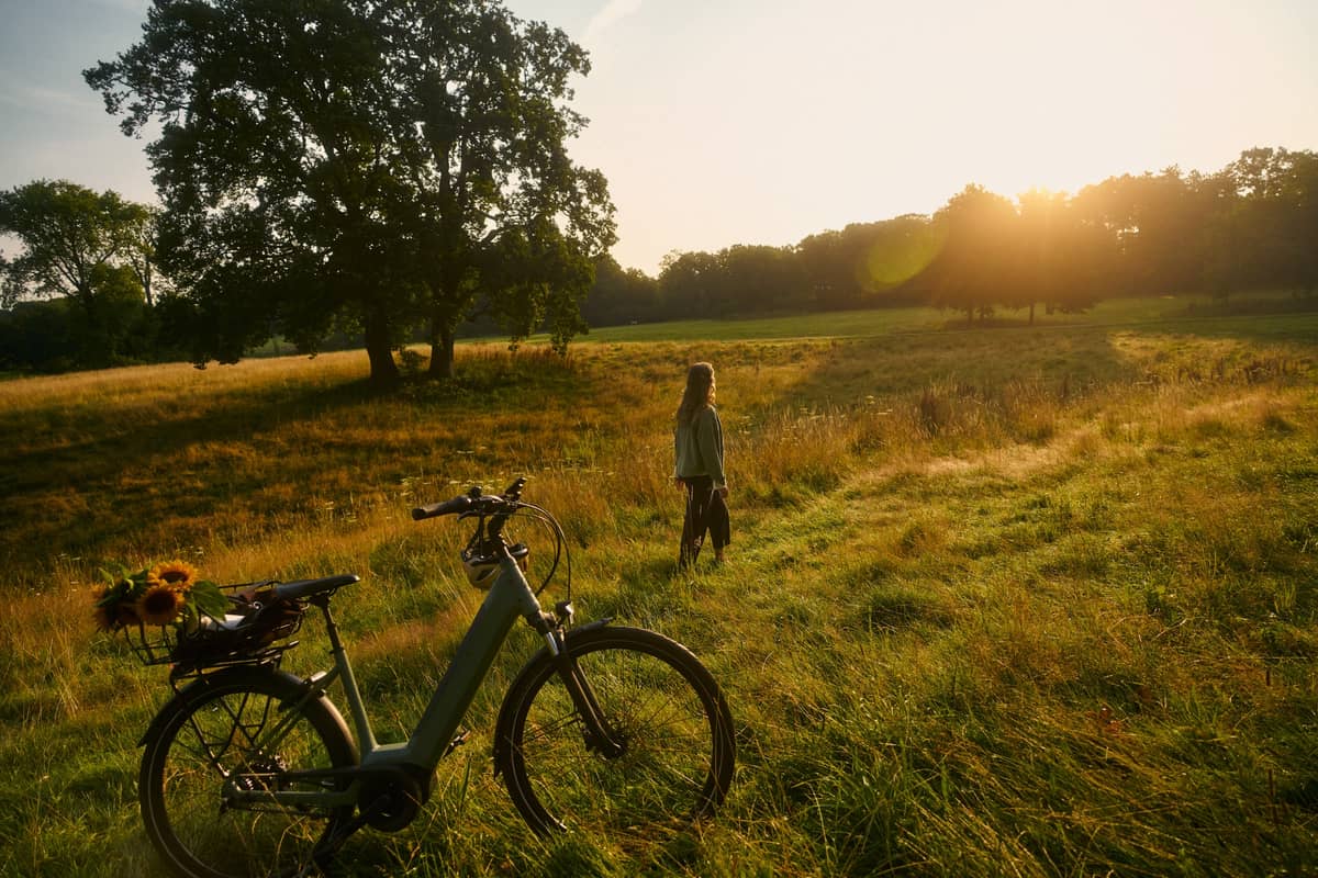 Woman with e-bike and sunflowers in a field