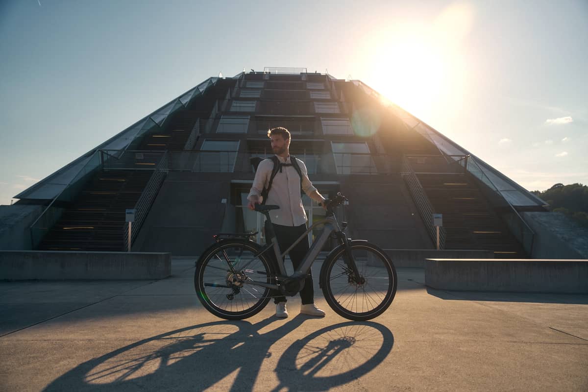 Man with e-bike in front of modern office building