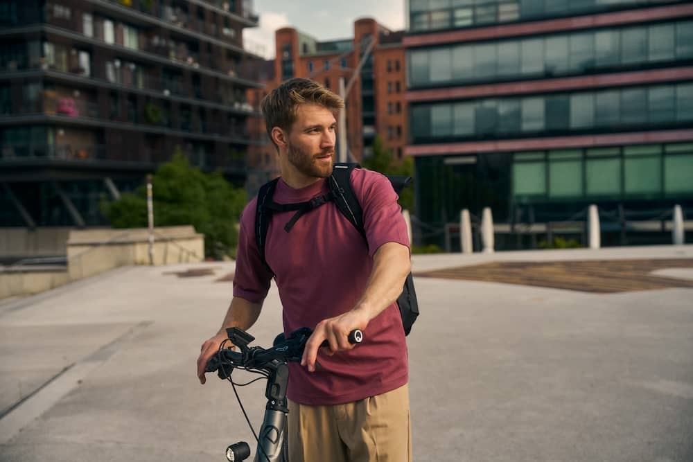 Mann steht mit Bike vor Geschäftsgebäude