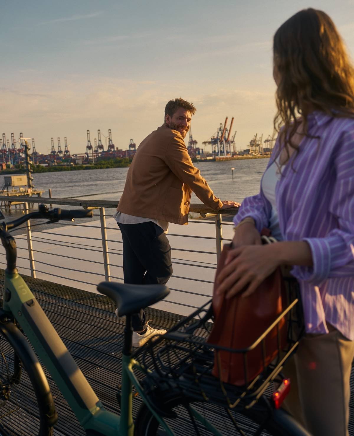 Frau und Mann neben Kalkhoff fahrrad stehen vor Hafenkulisse und schauen sich an