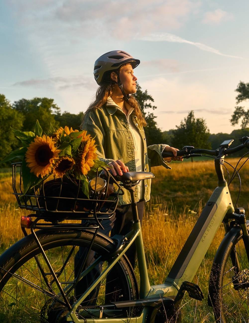 Woman with bicycle helmet and sunflowers in bicycle basket