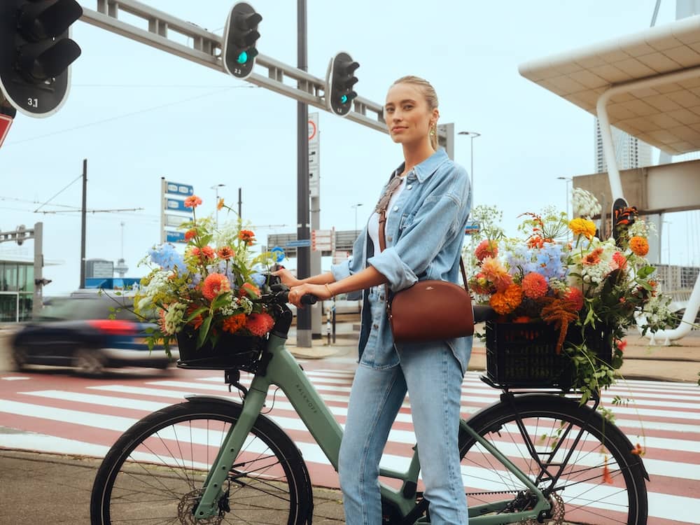 Frau mit E-Bike und Blumen in Fahrradkörben