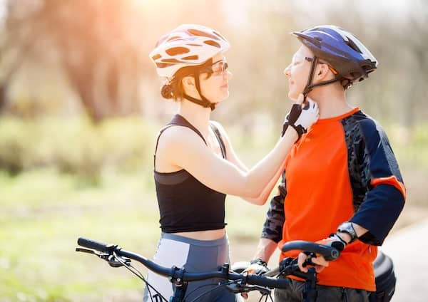 Sportliche Radfahrerin mit Betriebsfahrrad Schliesst Fahrradhelm Ihres Begleiters