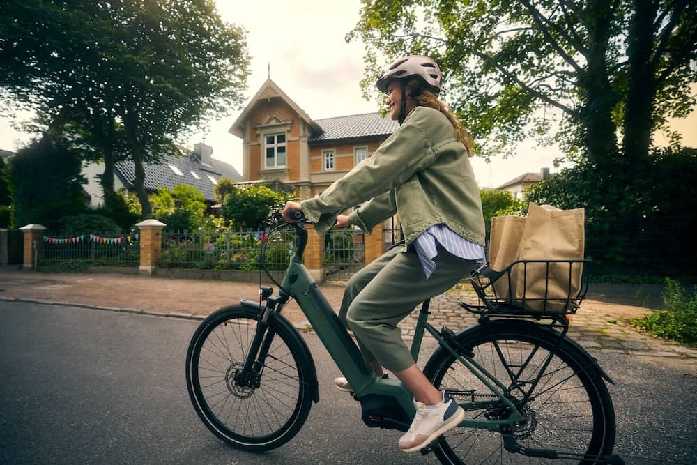 Frau auf E-Bike mit Einkäufen im Korb