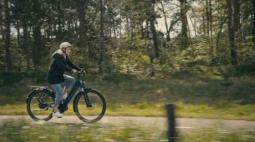 Woman riding bike on bike path in green surrounding