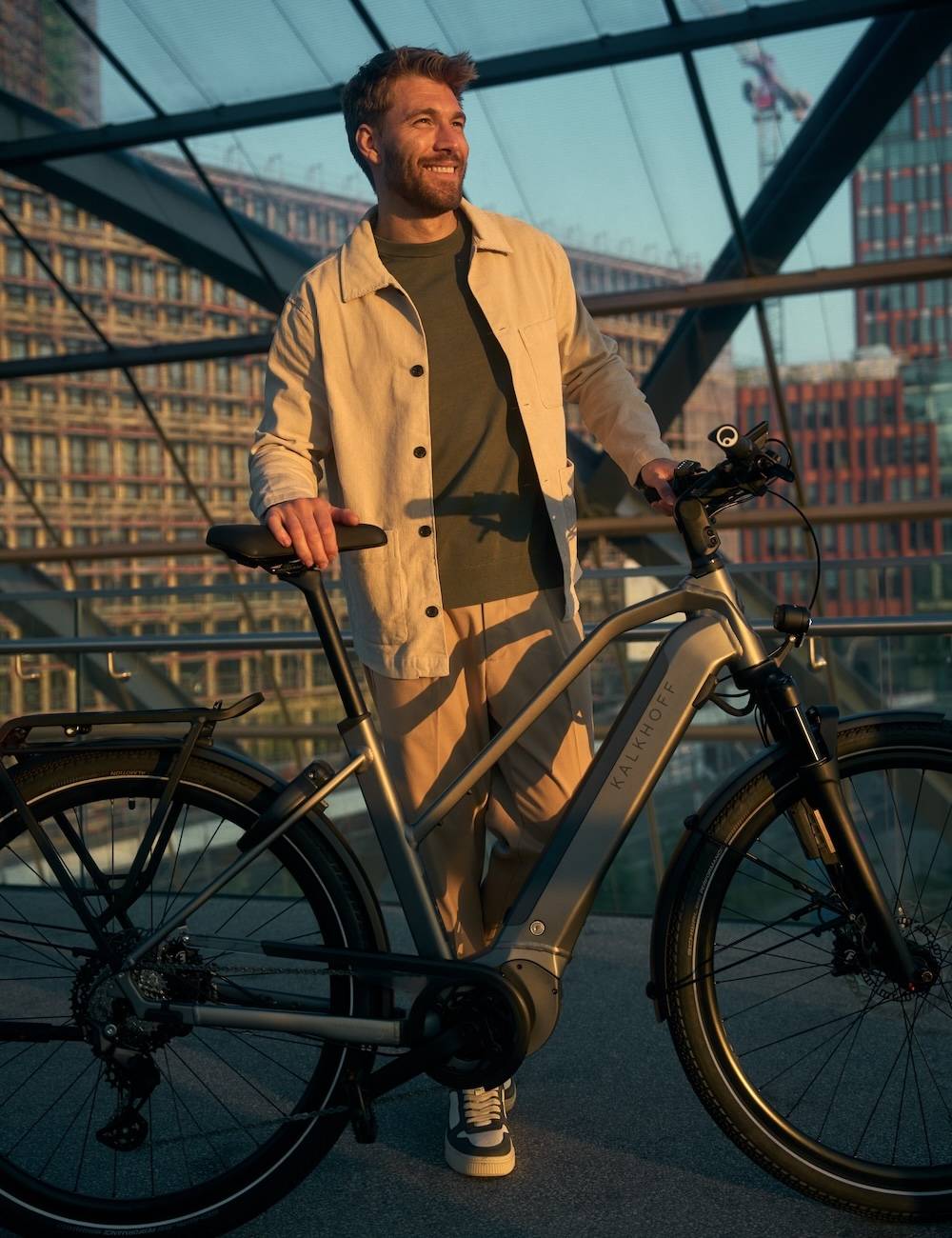 Man stands with his e-bike in front of a glass front