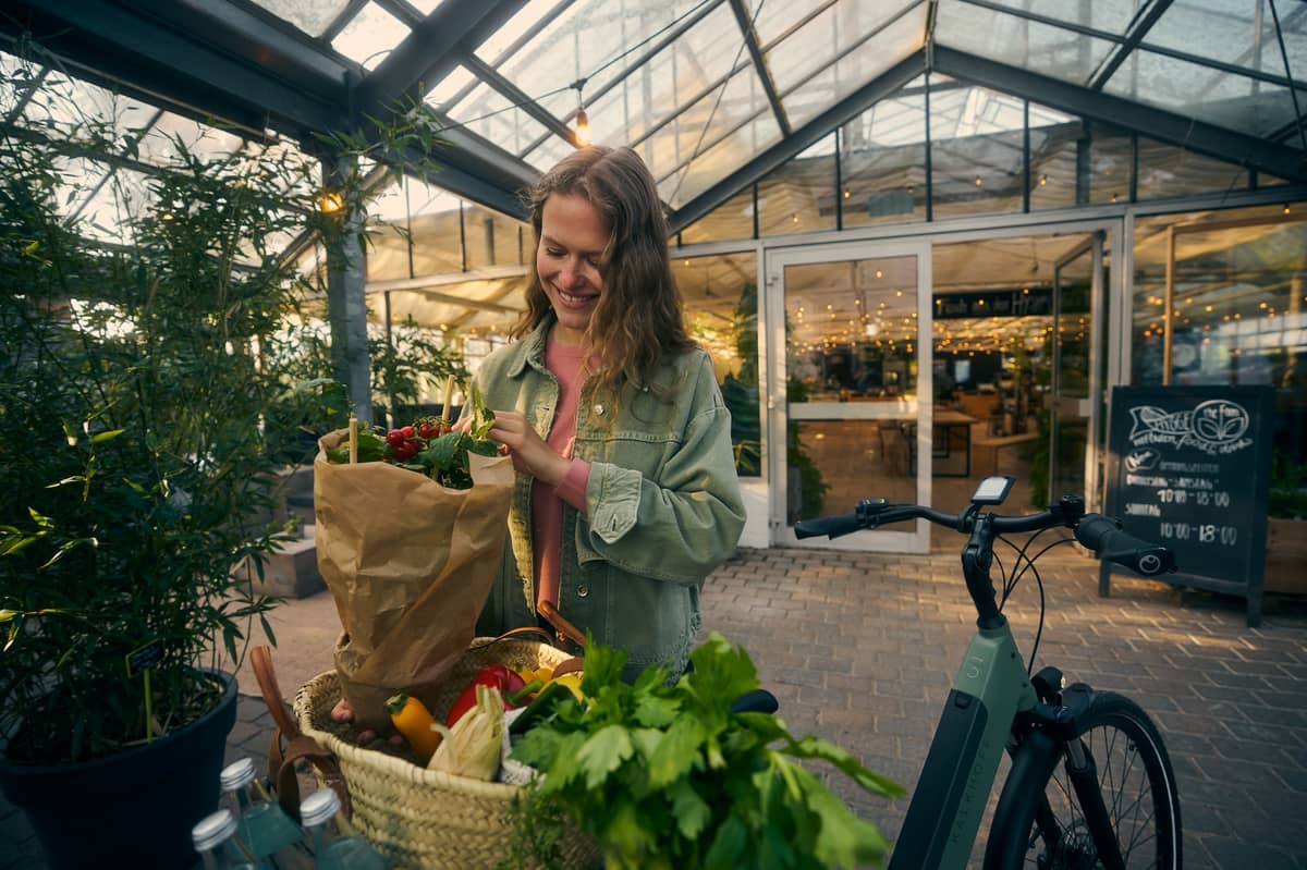 Woman standing next to bike smiling in front of supermarket