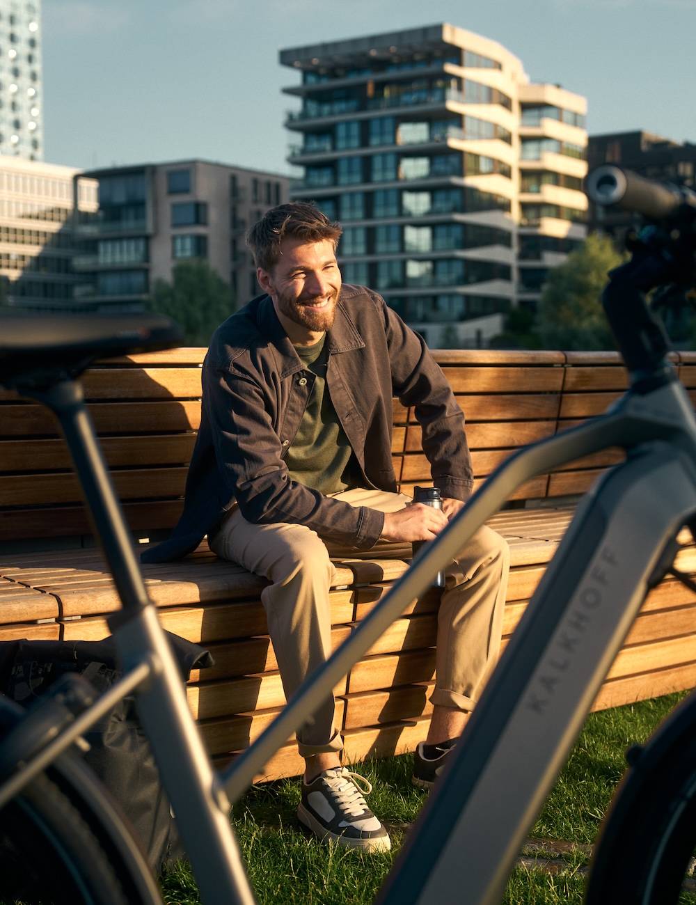 Man sits on a wooden bench behind his e-bike