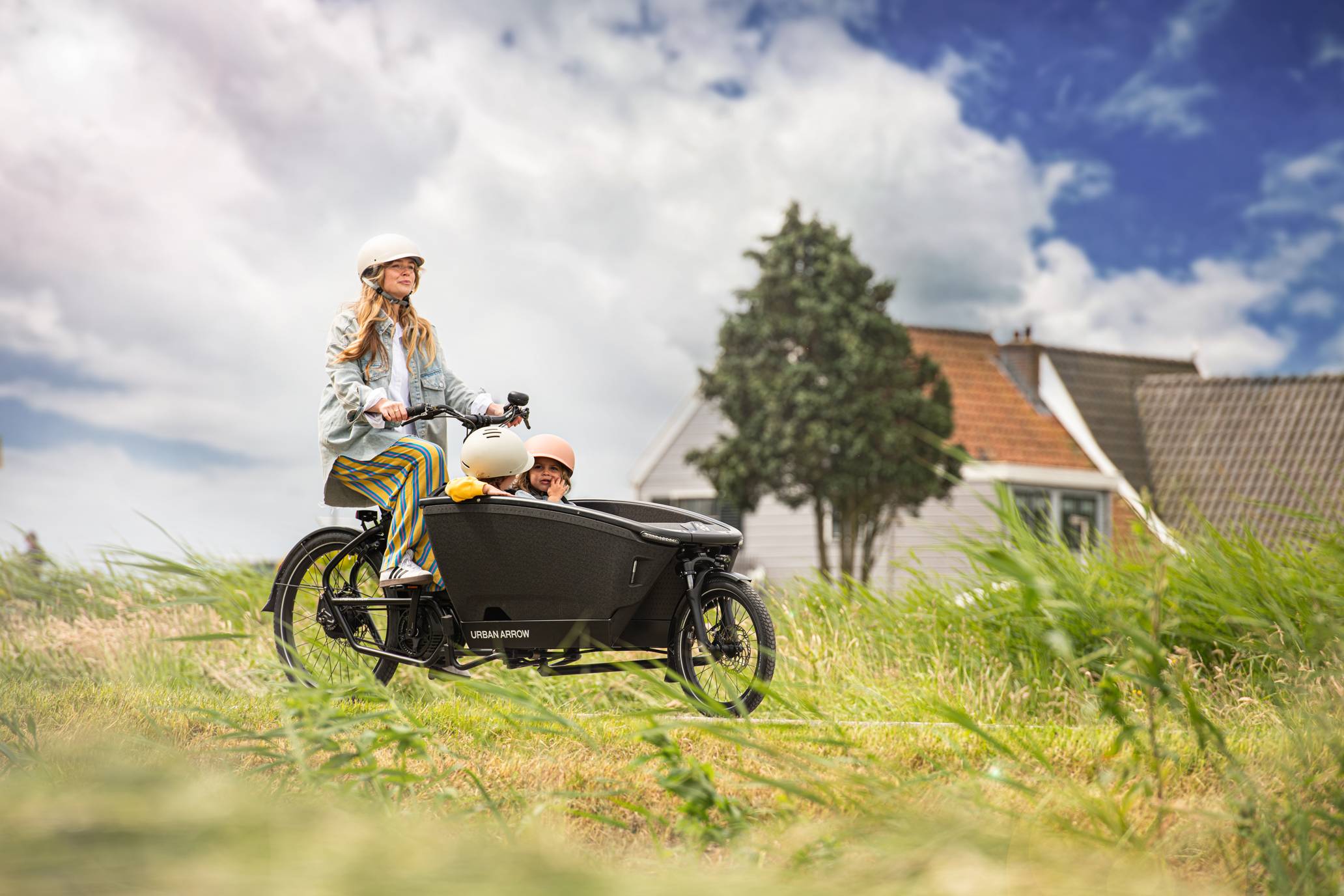 Woman with two kids on cargo bike in nature