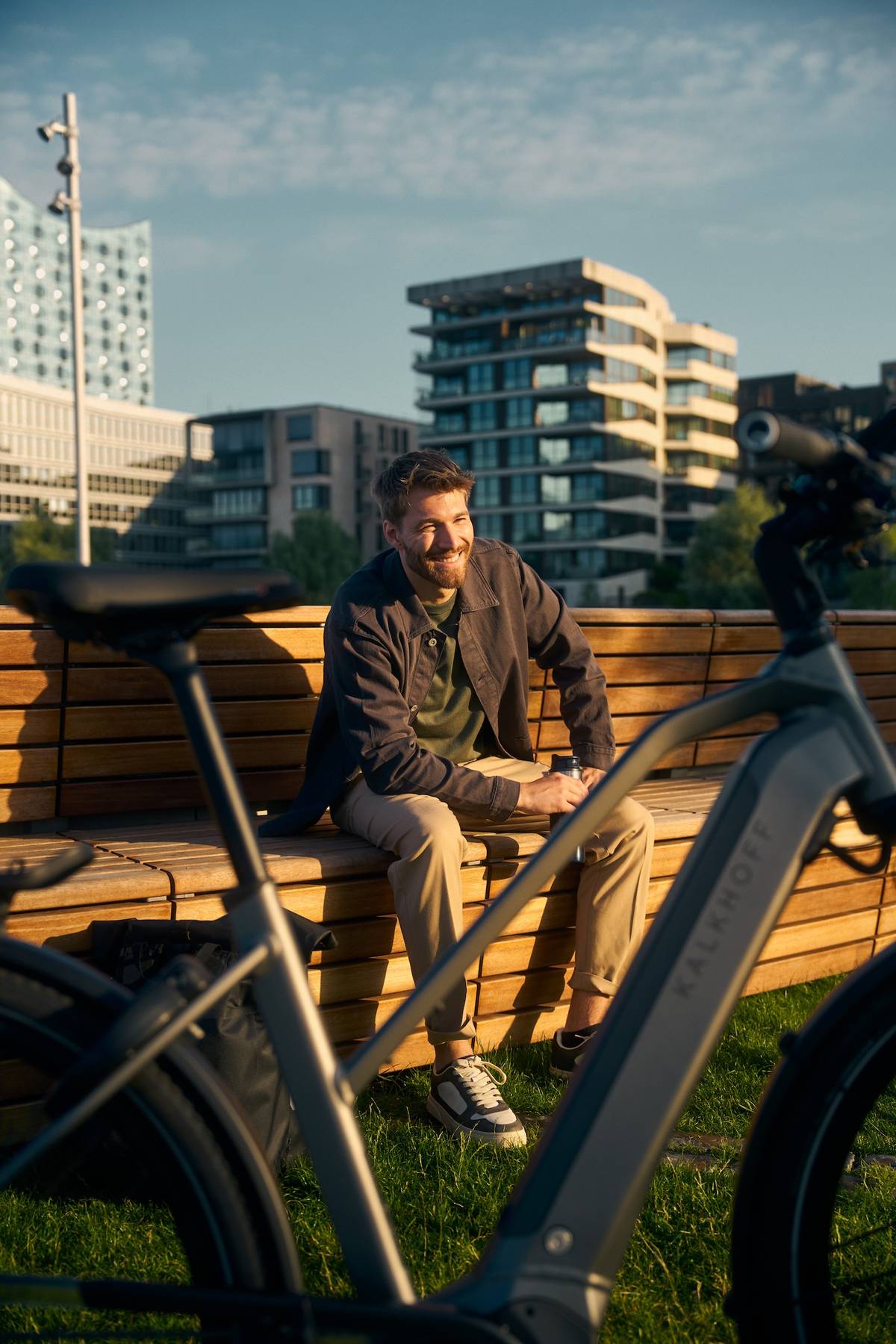 Mann sitzt lachend auf Bank, vor ihm steht ein Kalkhoff Jobbike