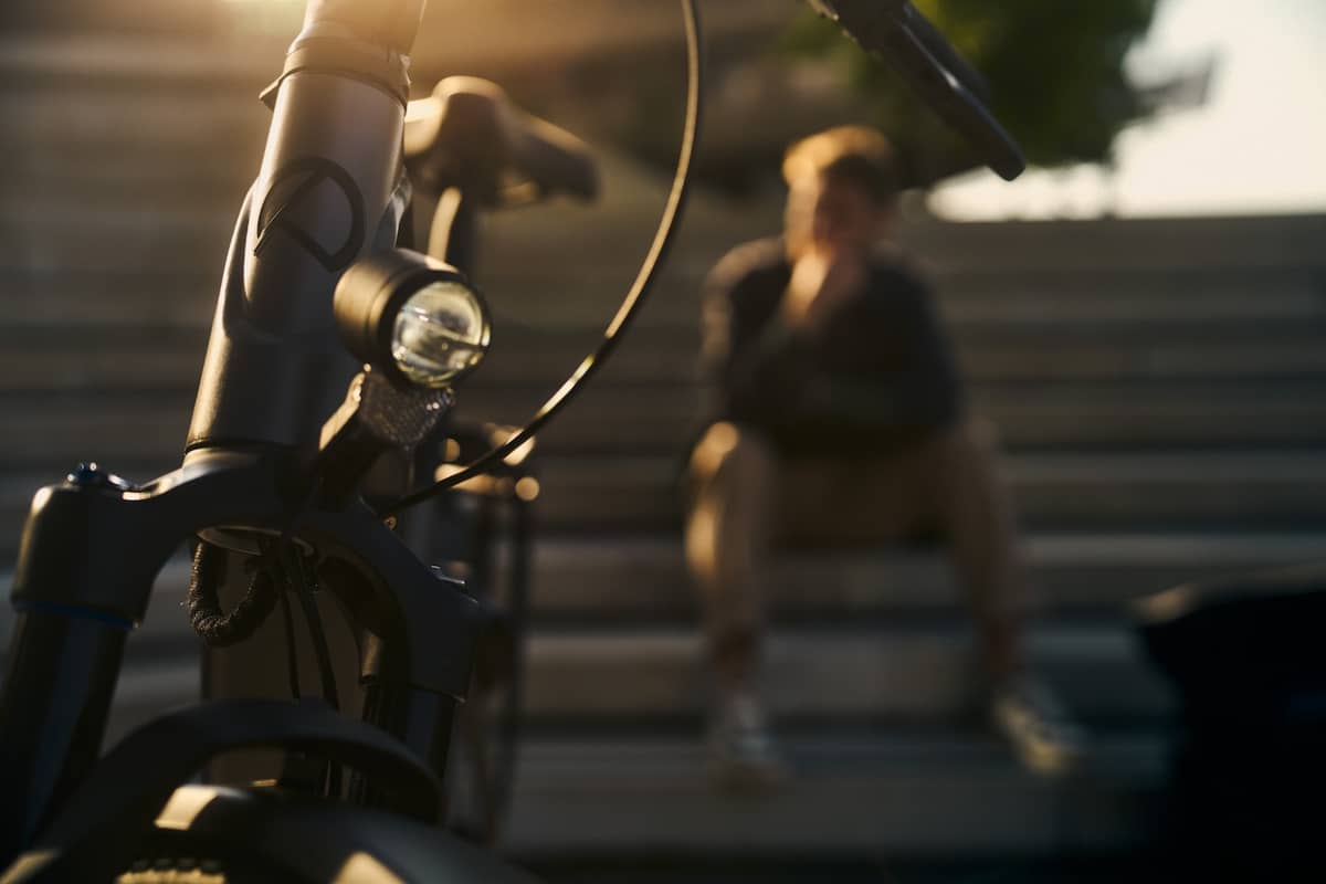 Kalkhoff Fahrrad steht im Vordergrund und Person sitzt auf Bank im Hintergrund