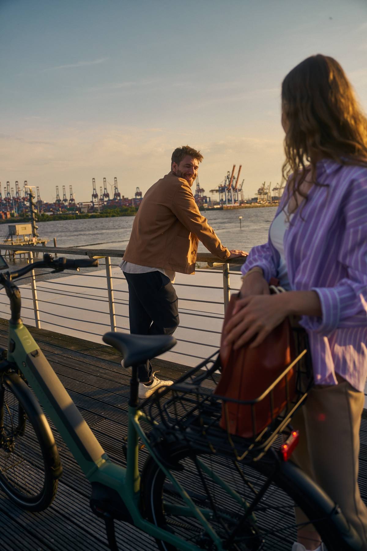 Frau und Mann neben Kalkhoff fahrrad stehen vor Hafenkulisse und schauen sich an