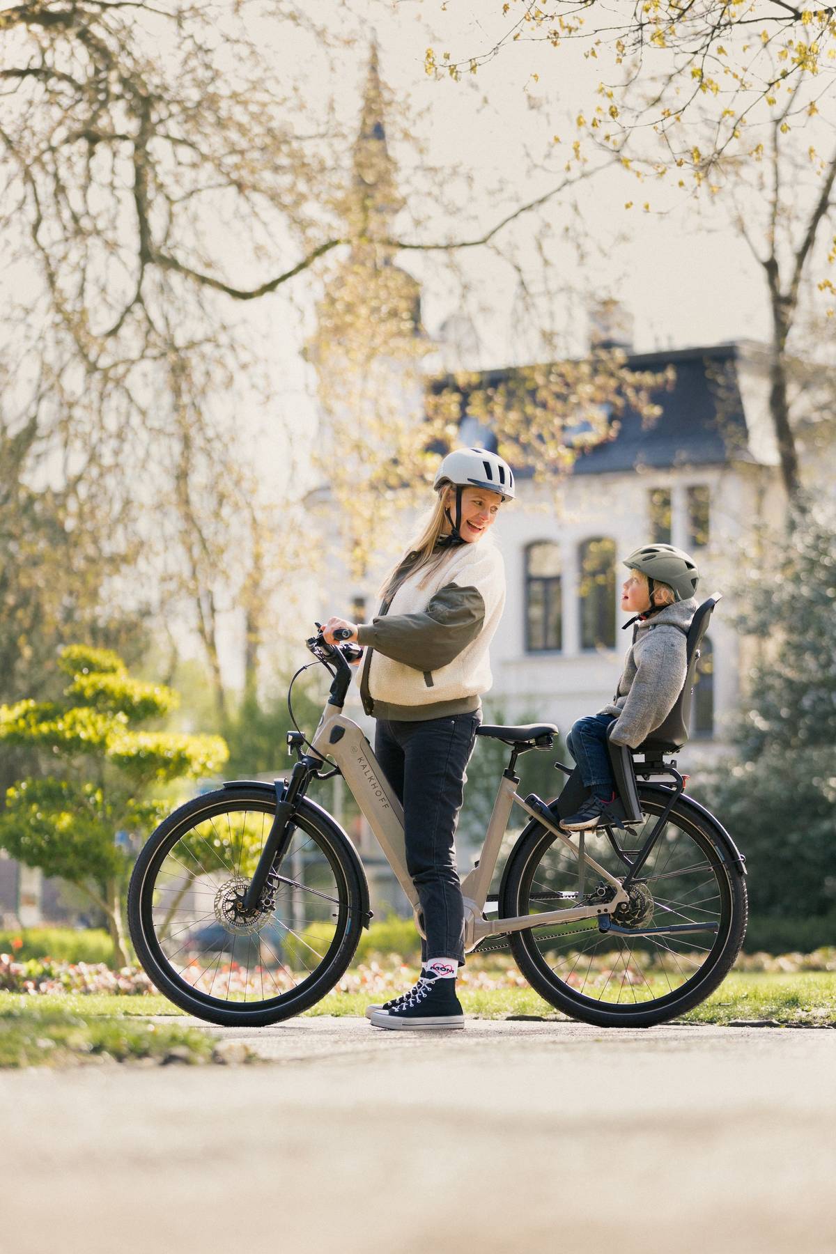 Schwangere Frau schaut zu Kind in Fahrradsitz